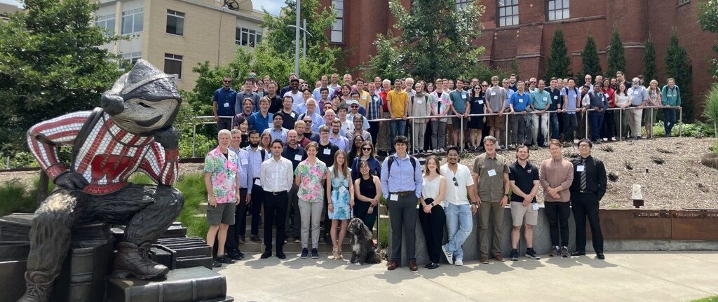 Attendees from the conference pose outside with a statue of Bucky Badger.