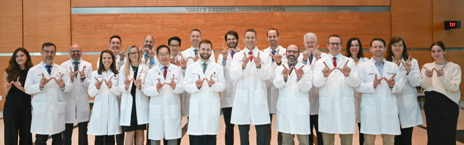 Abdominal imaging and intervention faculty pose for a group photo, holding their hands in a 'w' position for Wisconsin.