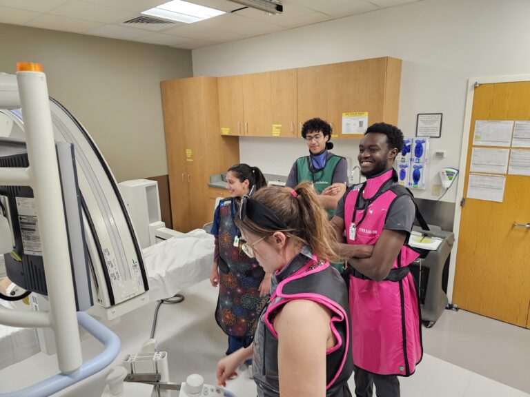 Students look on as Monica Cooley, MD works with the medical equipment for the demonstration.