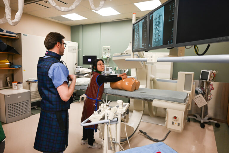 Nicolas Laucis, MD watches on as Qiuwen Quan participates in the spinal intervention session.
