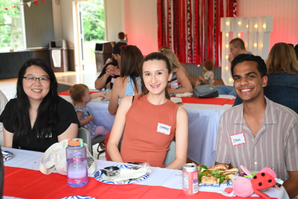 Sarah, Ishan, and another resident sitting with food at the table
