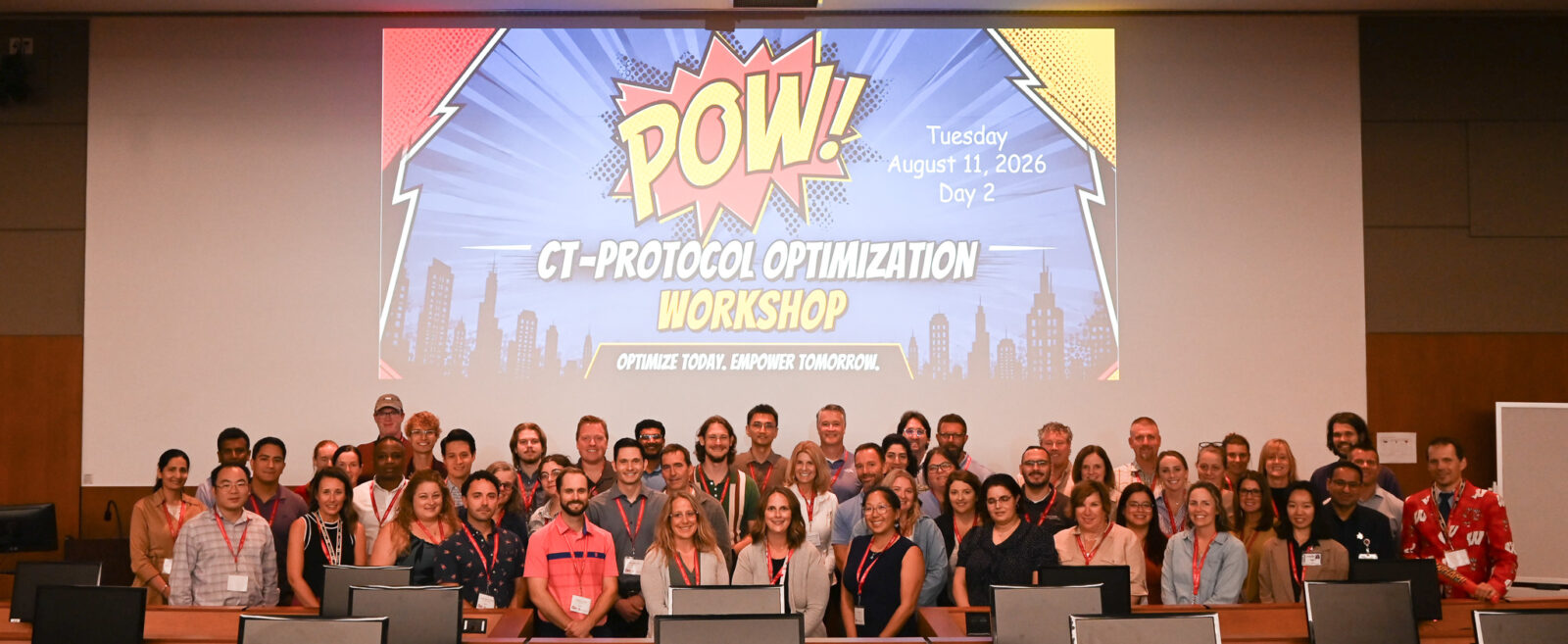 A large group of people pose for a photo in a lecture hall.