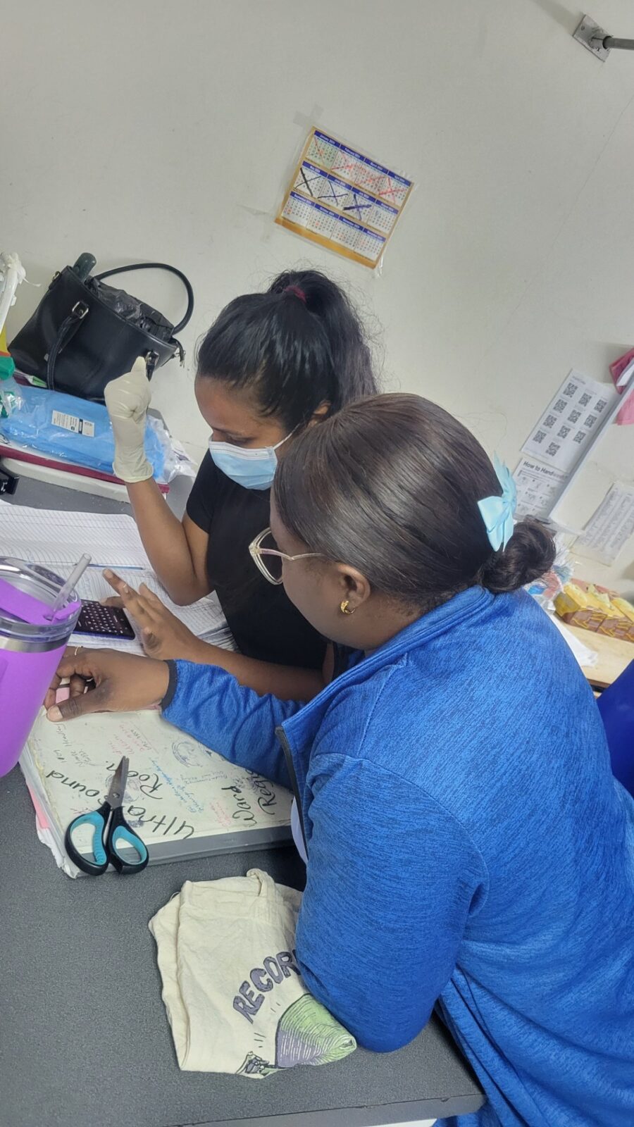 Nurses leaning over a table.