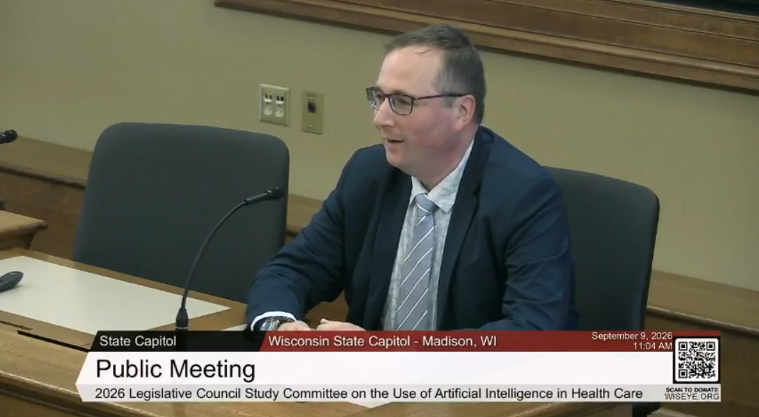 A screenshot from Wiseye showing Richard Bruce, MD presenting at a desk with a mic.