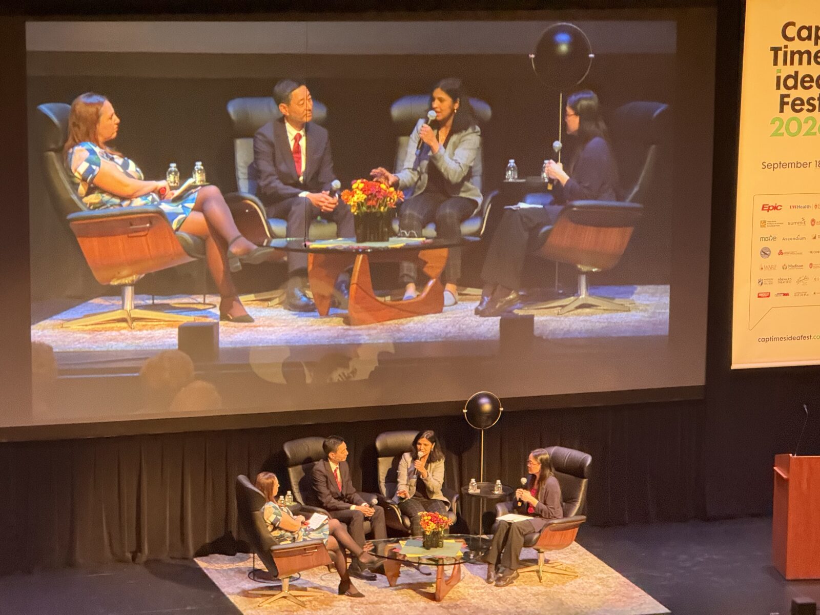Panelists sit in chairs on a stage answering questions.